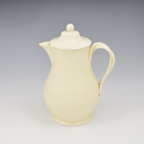 fig 1. An 18th-century creamware hot water jug featuring a baluster-shaped earthenware body, a fitted dome cover with a ball finial, and a loop handle.
