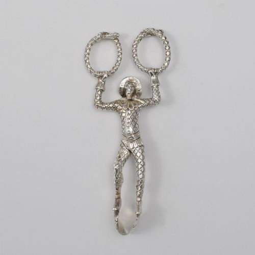 fig 1. A George IV sterling silver novelty sugar tong designed as a Harlequin figure holding circular ring handles above its head.
