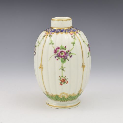 fig 1. An 18th-century fluted white porcelain tea canister decorated with hand-painted floral swags, gilded trim, and a cobalt blue pattern around the neck.