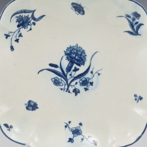 fig 1. A square soft-paste porcelain dessert dish with scalloped edges, decorated in underglaze blue with a central carnation motif and surrounding floral sprigs.