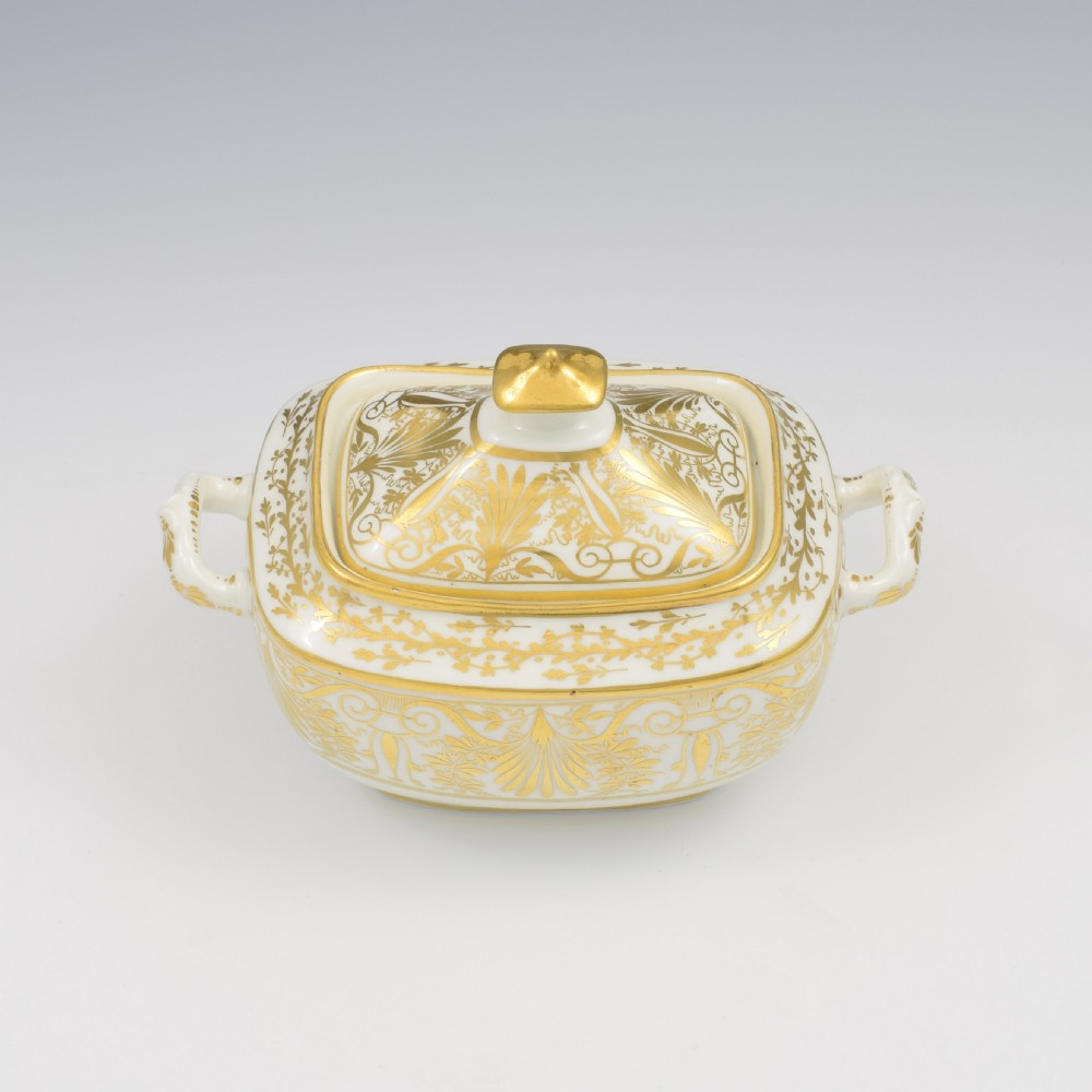 A white and gold Regency Spode porcelain sugar box with original lid, featuring loop handles and Neoclassical gilt scroll patterning. View X