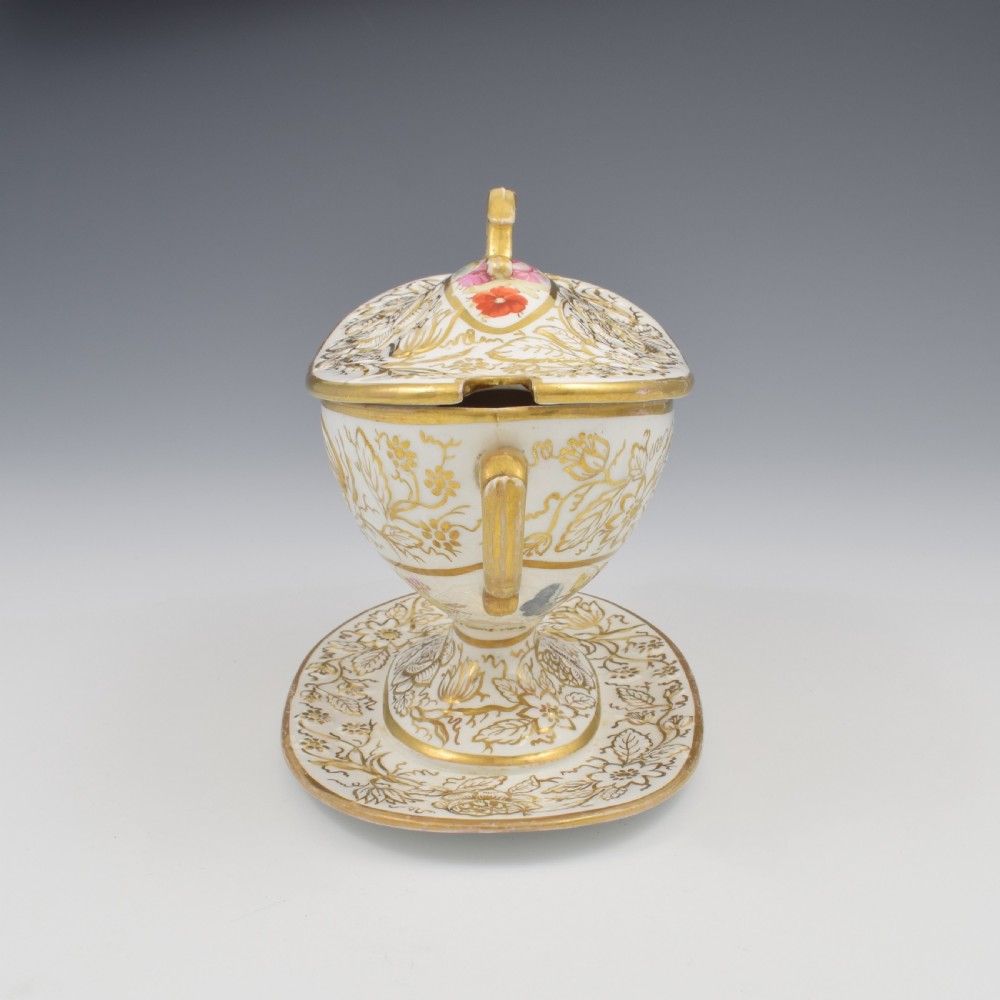 A Regency era white porcelain sauce tureen featuring gilded floral designs, hand-painted botanical flowers, twin side handles, and a matching stand. View VI