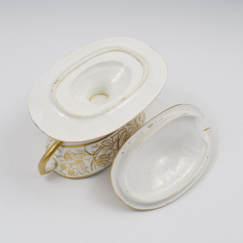 A Regency era white porcelain sauce tureen featuring gilded floral designs, hand-painted botanical flowers, twin side handles, and a matching stand. View XII