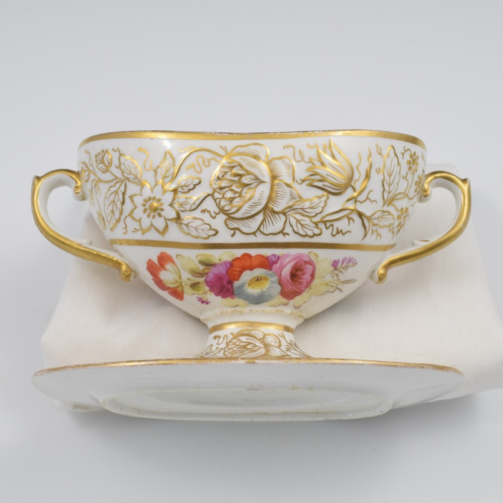 A Regency era white porcelain sauce tureen featuring gilded floral designs, hand-painted botanical flowers, twin side handles, and a matching stand. View XIV