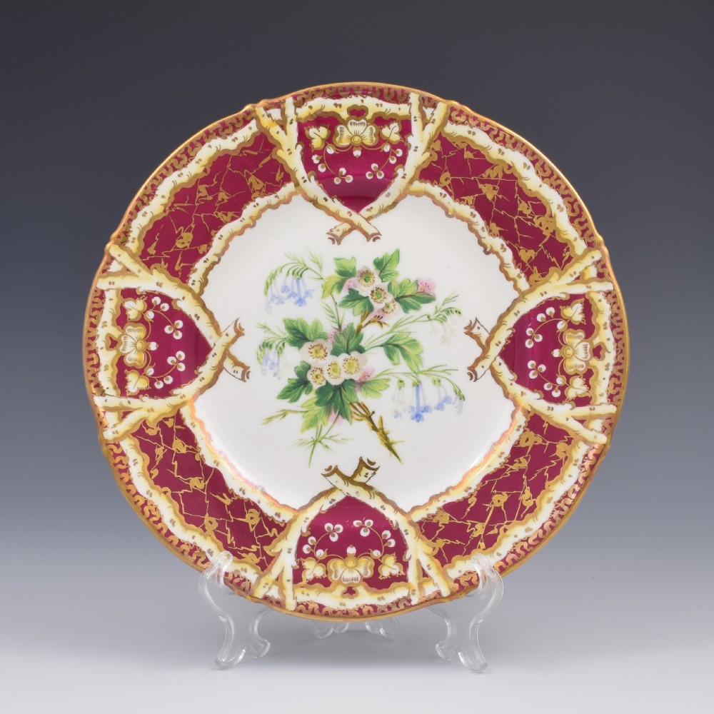 A circular Samuel Alcock porcelain dessert plate featuring a hand-painted botanical floral centre framed by a burgundy and gilt border.