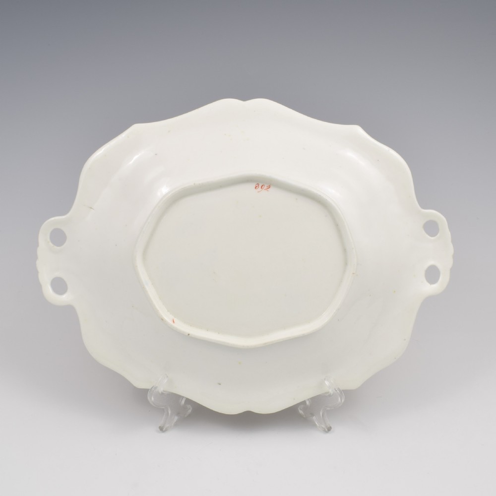 An oval antique Regency porcelain dessert dish featuring cobalt blue and gold scrollwork, hand-painted floral panels, and pierced handles. View IX