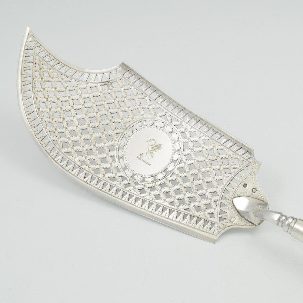 An 18th-century French silver fish slice with a pierced geometric lattice blade, an engraved crest, and a turned dark wood handle. View XII