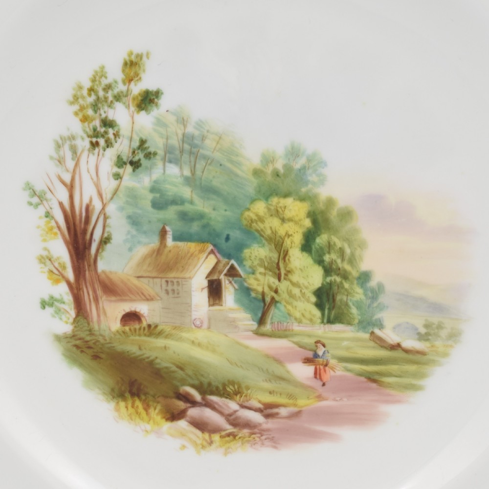 An antique porcelain dessert plate featuring a hand-painted pastoral landscape central vignette encircled by a pink border with gilded decoration and raised white enamel dots. View III