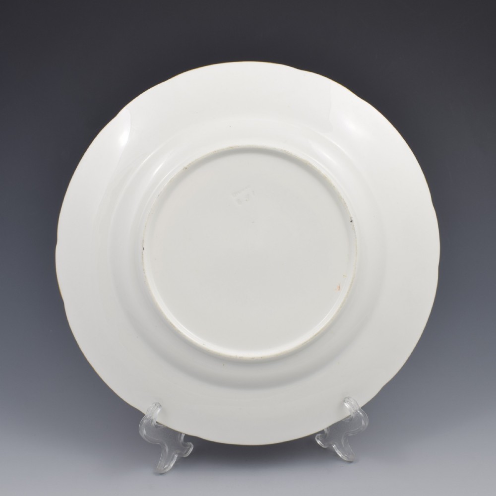 An antique porcelain dessert plate featuring a hand-painted pastoral landscape central vignette encircled by a pink border with gilded decoration and raised white enamel dots. View VI