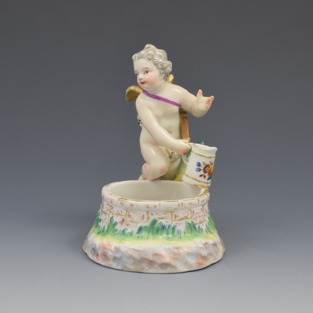 A 19th-century KPM Berlin porcelain table salt featuring a cupid figure standing beside a brick-patterned well basin with hand-painted details. View III