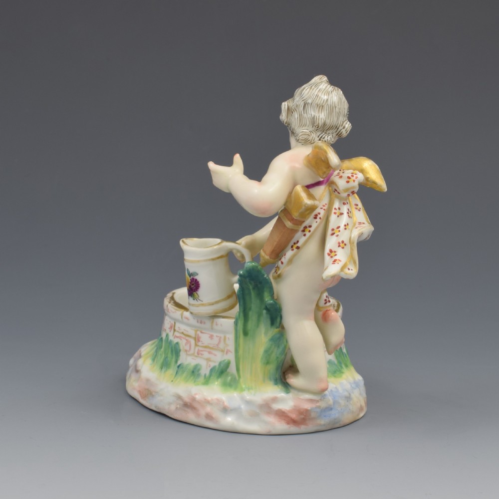 A 19th-century KPM Berlin porcelain table salt featuring a cupid figure standing beside a brick-patterned well basin with hand-painted details. View VI