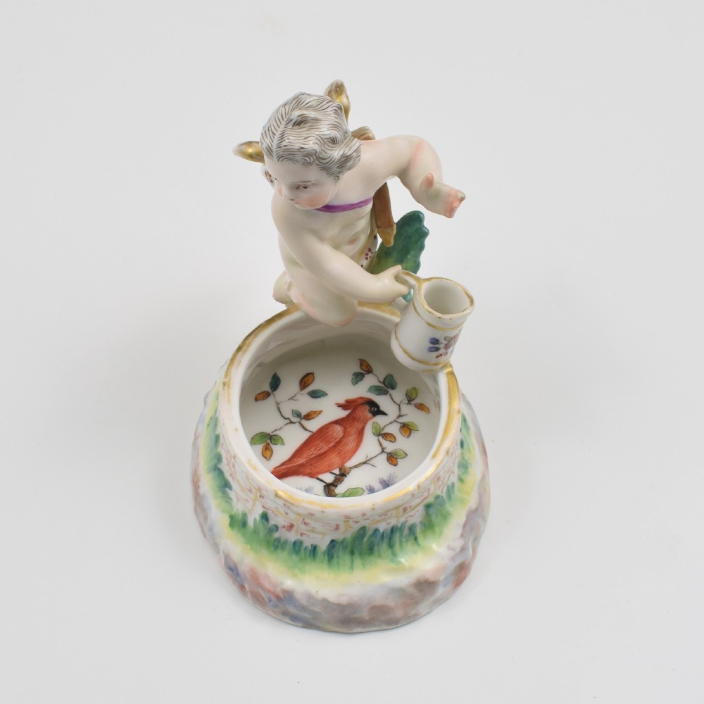 A 19th-century KPM Berlin porcelain table salt featuring a cupid figure standing beside a brick-patterned well basin with hand-painted details. View IX