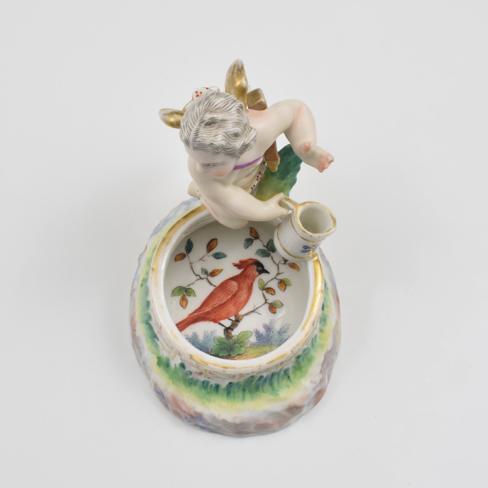 A 19th-century KPM Berlin porcelain table salt featuring a cupid figure standing beside a brick-patterned well basin with hand-painted details. View XII