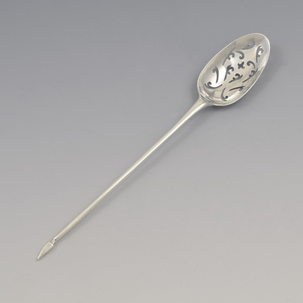 A George II sterling silver mote spoon with a pierced scrollwork bowl and a slender stem terminating in a pointed tip.