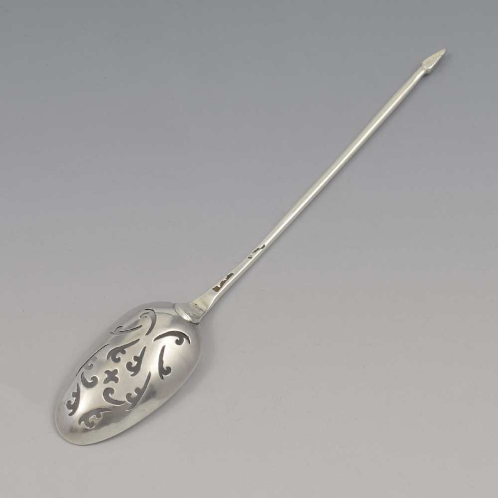 A George II sterling silver mote spoon with a pierced scrollwork bowl and a slender stem terminating in a pointed tip. View X