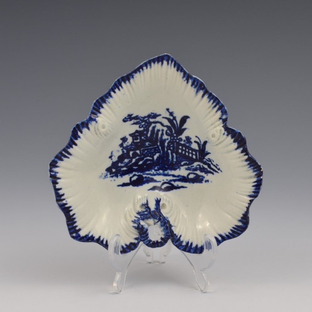 A leaf-shaped 18th-century Liverpool soft-paste porcelain pickle dish decorated with an underglaze blue chinoiserie landscape and feathered blue rim.