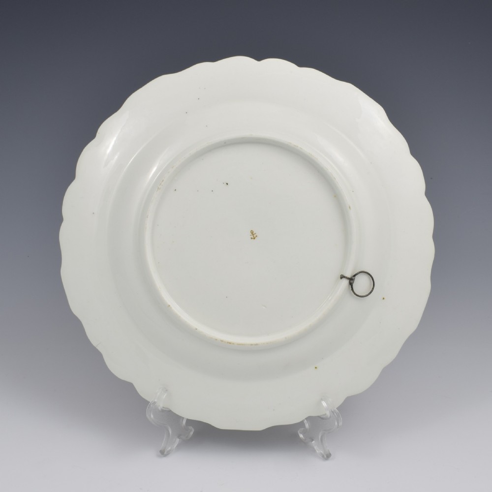 An eighteenth-century soft-paste porcelain dessert plate with a lobed gilded rim, decorated with hand-painted fruit motifs and insects against a white background. View VI