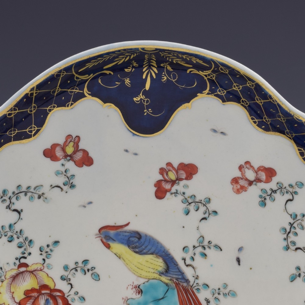 An eighteenth-century shell-shaped soft-paste porcelain dessert dish featuring a hand-painted exotic bird, floral motifs, and a cobalt blue border detailed with gilded lattice work. View III