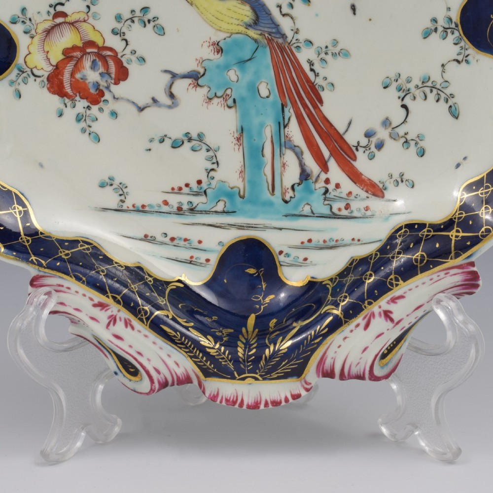 An eighteenth-century shell-shaped soft-paste porcelain dessert dish featuring a hand-painted exotic bird, floral motifs, and a cobalt blue border detailed with gilded lattice work. View IV