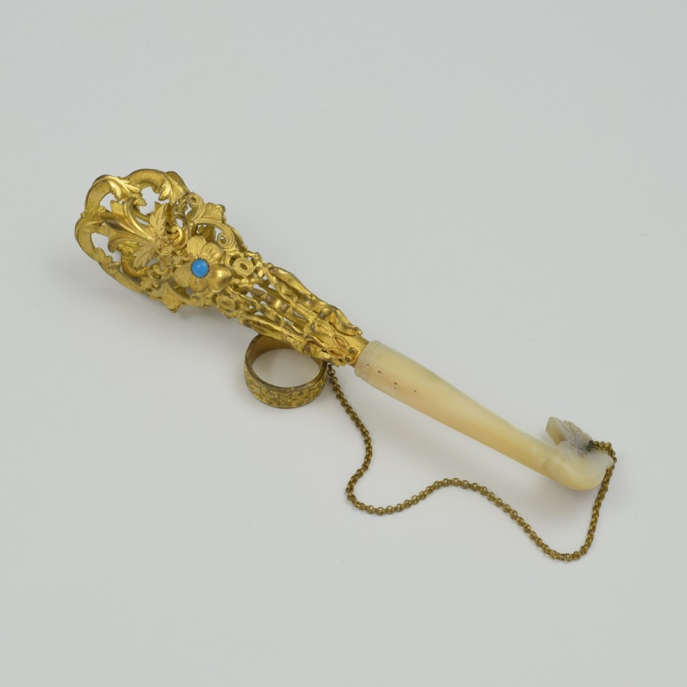 An antique French gilt ormolu tussie mussie posy holder featuring elaborate pierced metalwork set with a turquoise stone, a carved mother-of-pearl handle, and a finger ring attached by a chain. View V