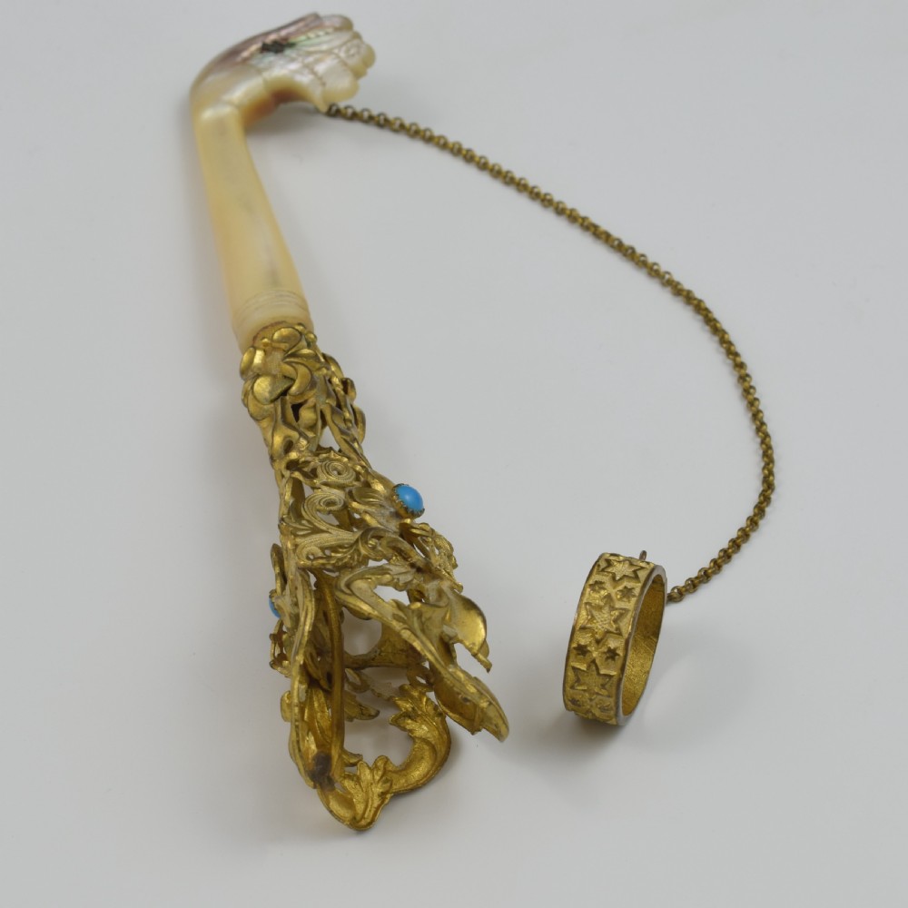 An antique French gilt ormolu tussie mussie posy holder featuring elaborate pierced metalwork set with a turquoise stone, a carved mother-of-pearl handle, and a finger ring attached by a chain. View VII