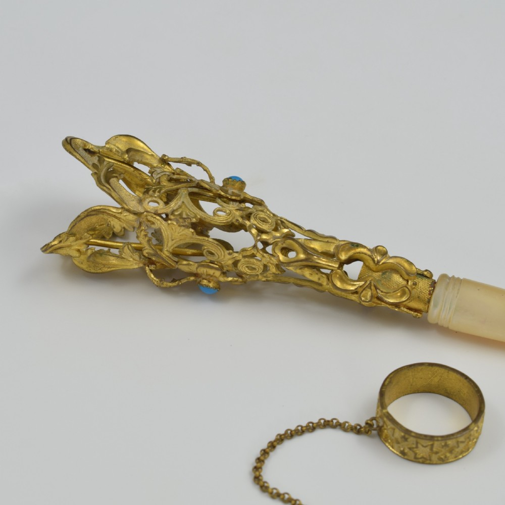 An antique French gilt ormolu tussie mussie posy holder featuring elaborate pierced metalwork set with a turquoise stone, a carved mother-of-pearl handle, and a finger ring attached by a chain. View XI
