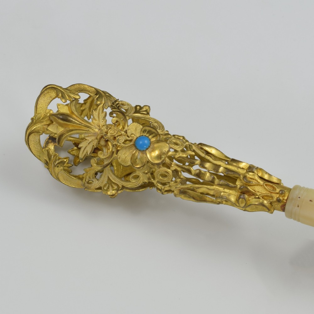 An antique French gilt ormolu tussie mussie posy holder featuring elaborate pierced metalwork set with a turquoise stone, a carved mother-of-pearl handle, and a finger ring attached by a chain. View XIV