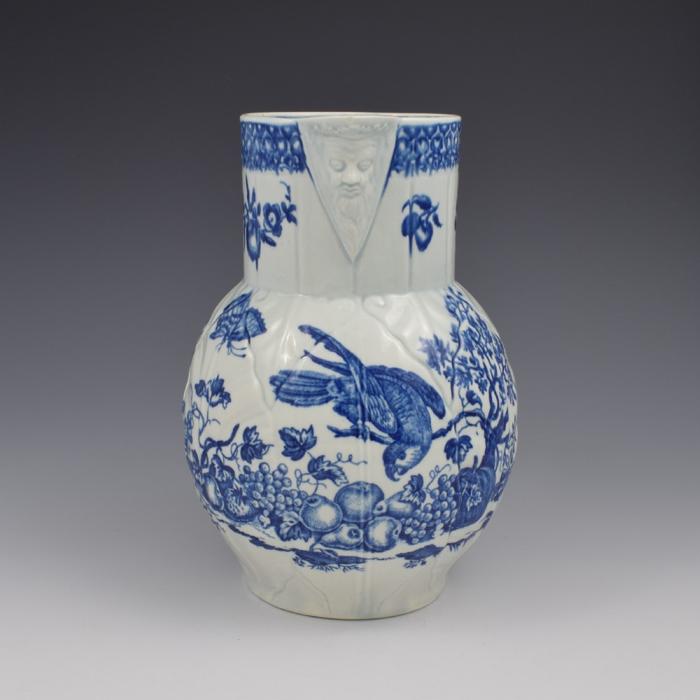 An 18th-century First Period Worcester soft-paste porcelain mask jug featuring cabbage-leaf moulding and blue and white printed foliage motifs. View IV