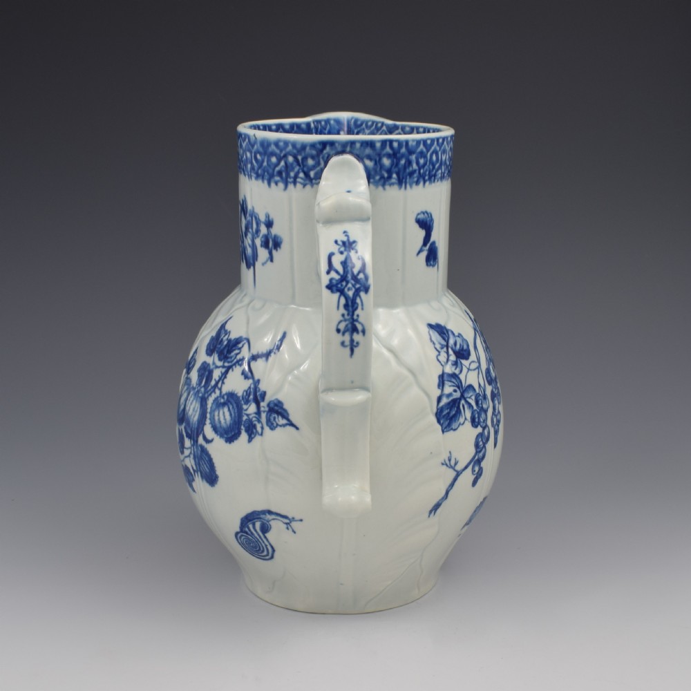 An 18th-century First Period Worcester soft-paste porcelain mask jug featuring cabbage-leaf moulding and blue and white printed foliage motifs. View VII