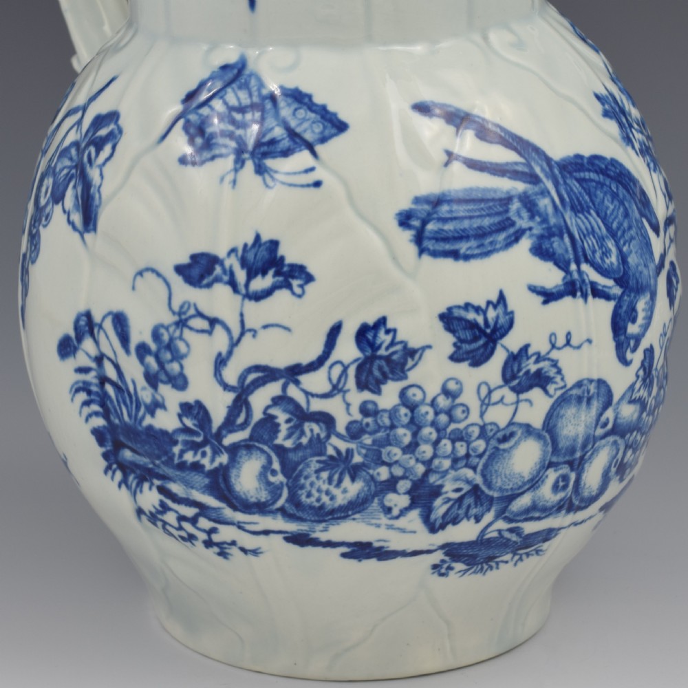 An 18th-century First Period Worcester soft-paste porcelain mask jug featuring cabbage-leaf moulding and blue and white printed foliage motifs. View XI