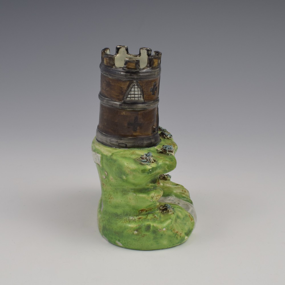 An antique Staffordshire pearlware spill vase shaped as a brown castellated turret standing over a green rocky bridge with a small boat underneath. View III