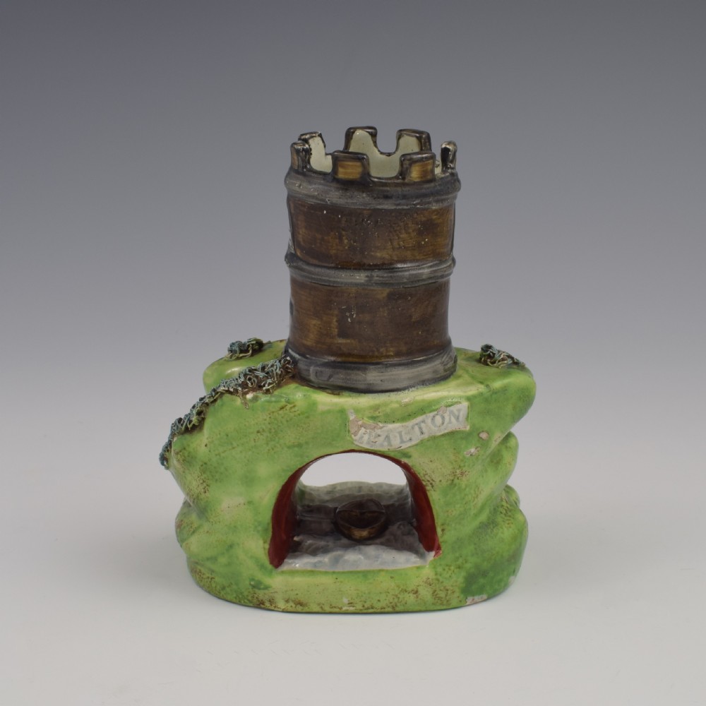 An antique Staffordshire pearlware spill vase shaped as a brown castellated turret standing over a green rocky bridge with a small boat underneath. View IV