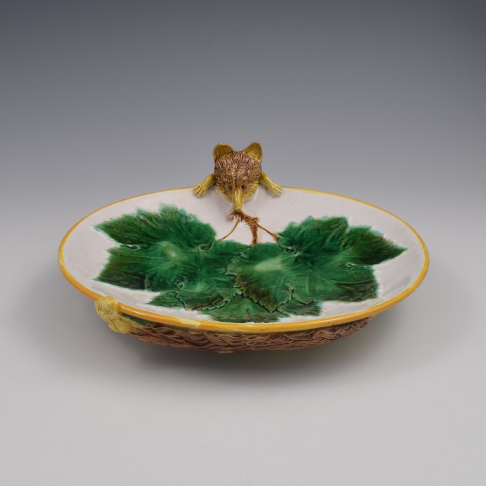 An oval Victorian majolica dish featuring a pink interior ground with raised green leaves and a sculpted fox head perched on the rim.