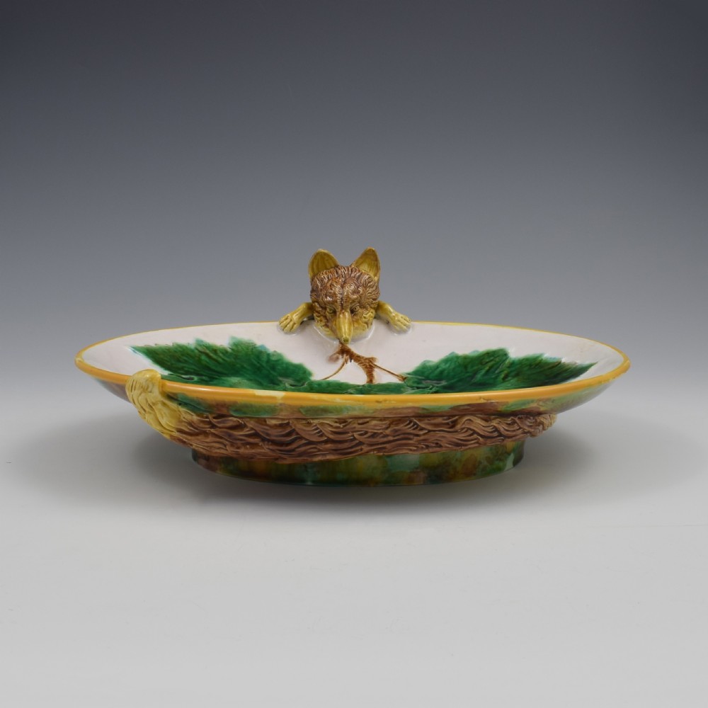An oval Victorian majolica dish featuring a pink interior ground with raised green leaves and a sculpted fox head perched on the rim. View II