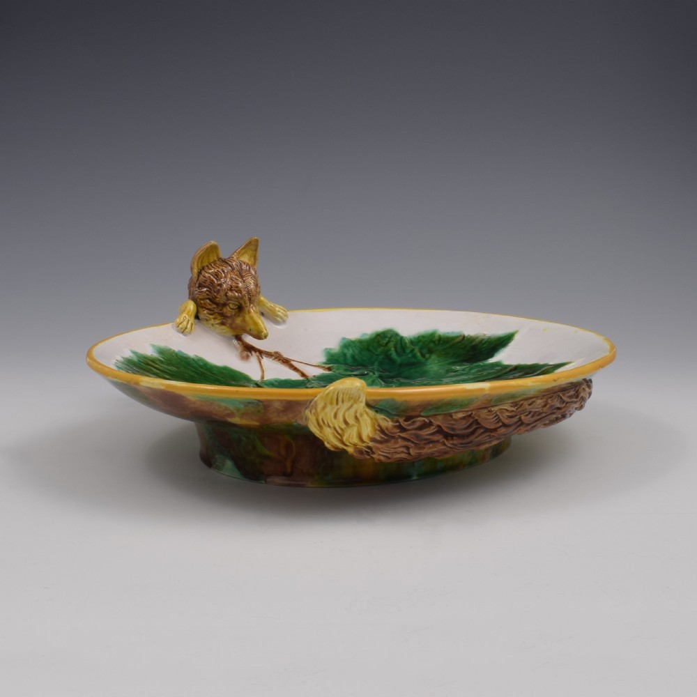 An oval Victorian majolica dish featuring a pink interior ground with raised green leaves and a sculpted fox head perched on the rim. View III