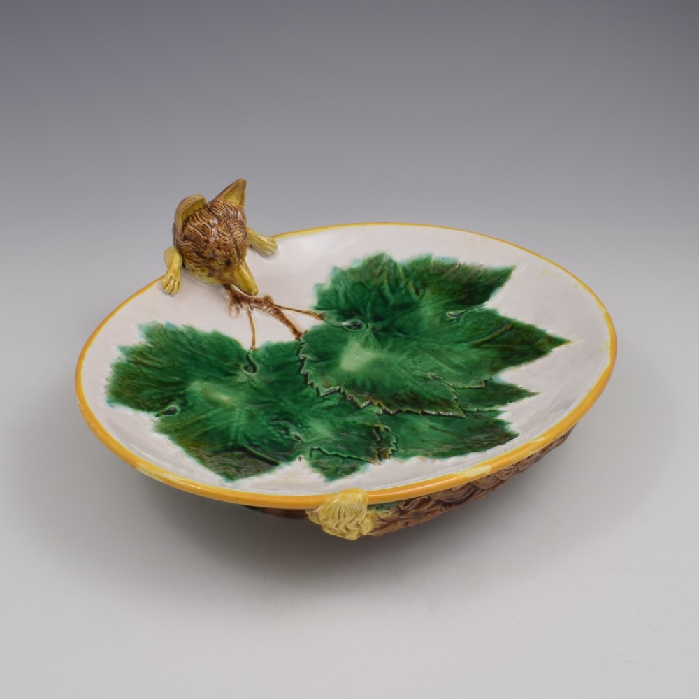 An oval Victorian majolica dish featuring a pink interior ground with raised green leaves and a sculpted fox head perched on the rim. View V