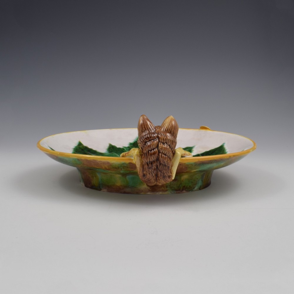 An oval Victorian majolica dish featuring a pink interior ground with raised green leaves and a sculpted fox head perched on the rim. View VII