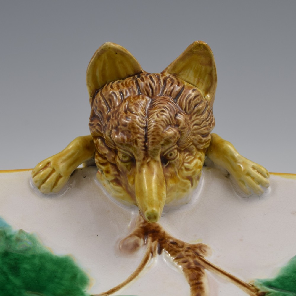 An oval Victorian majolica dish featuring a pink interior ground with raised green leaves and a sculpted fox head perched on the rim. View XI