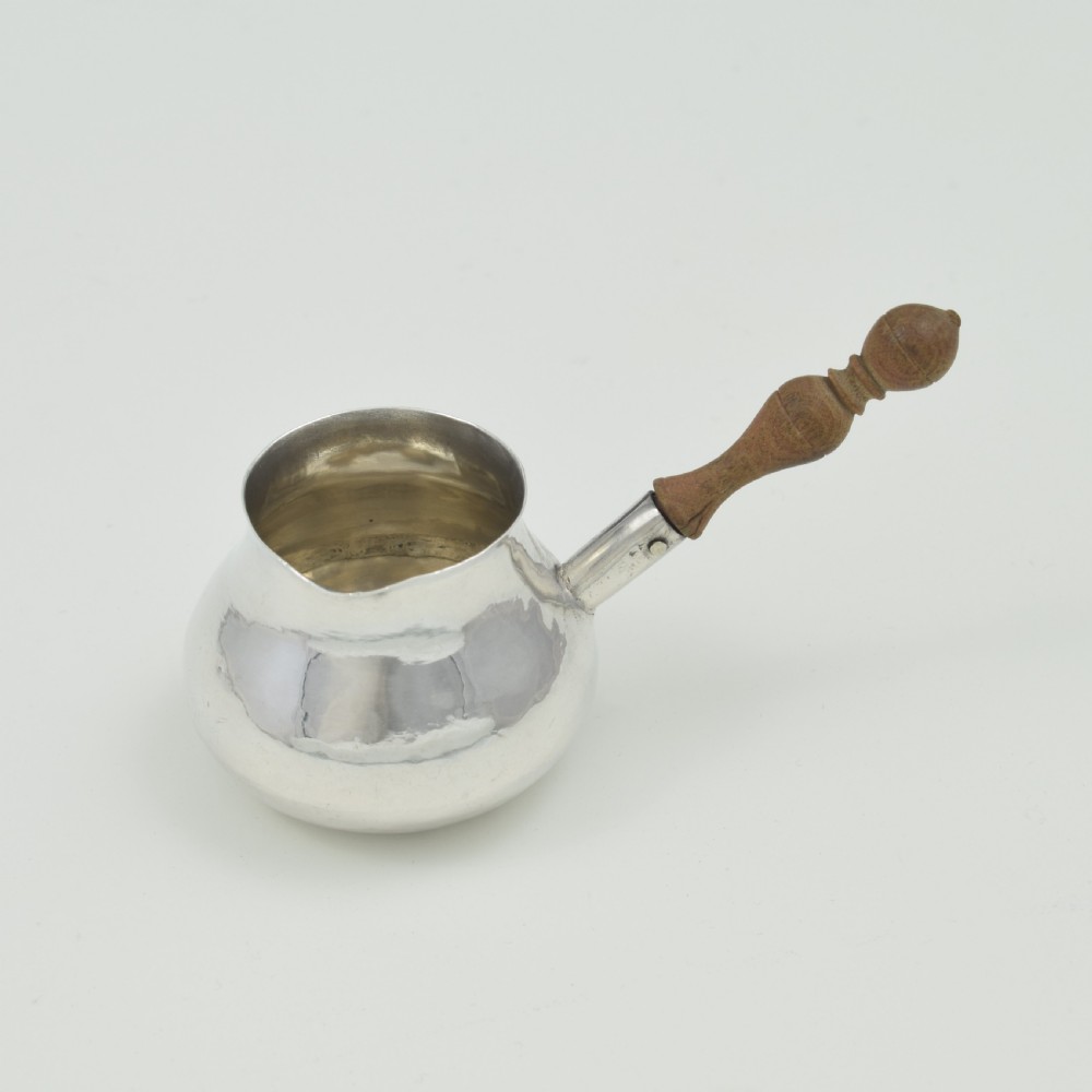A miniature George I sterling silver brandy warming pan featuring a bulbous body, small spout, and a turned wooden handle. View VII