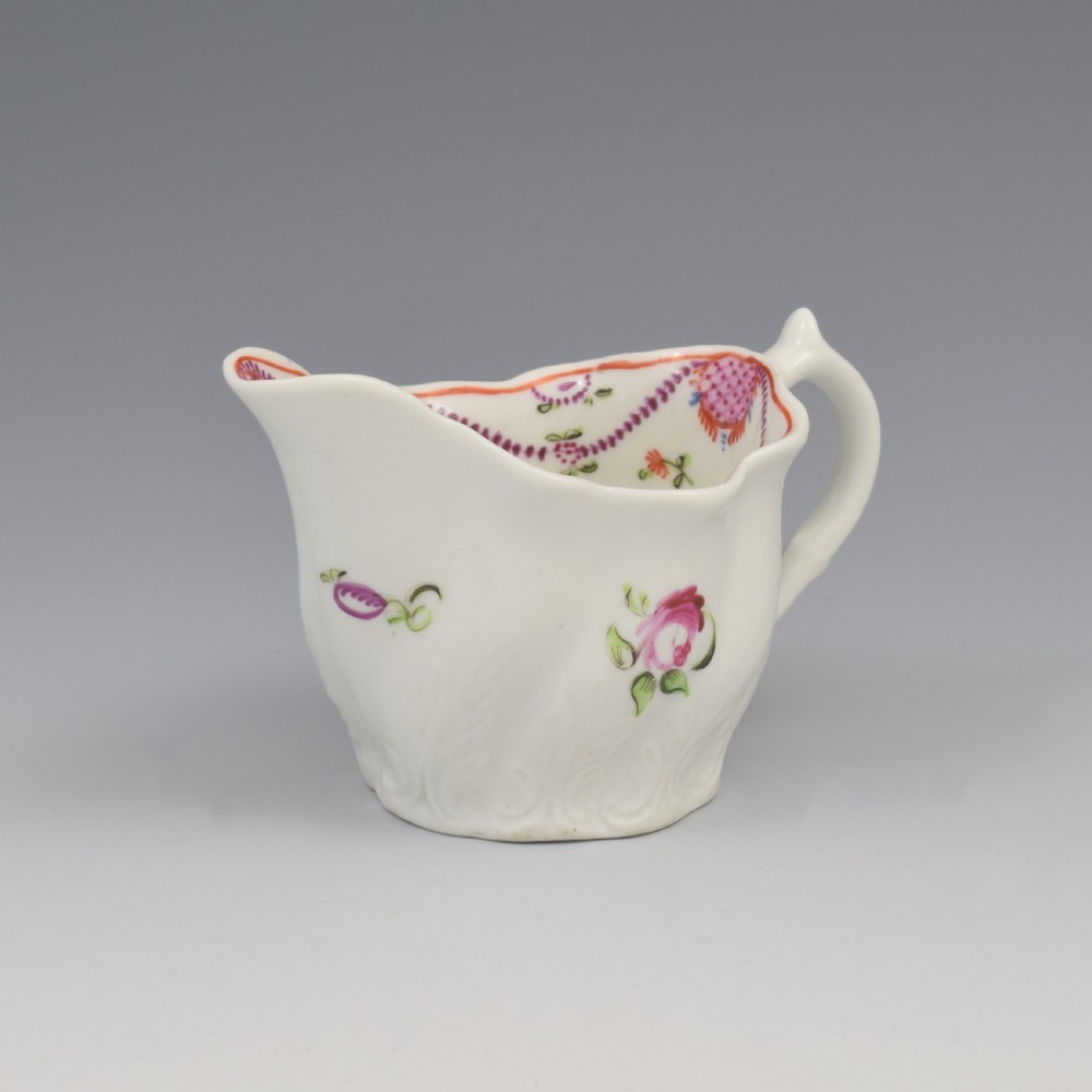 A white porcelain low Chelsea ewer cream jug featuring hand-painted pink floral sprigs, a moulded leaf base, and an ornate loop handle. View II