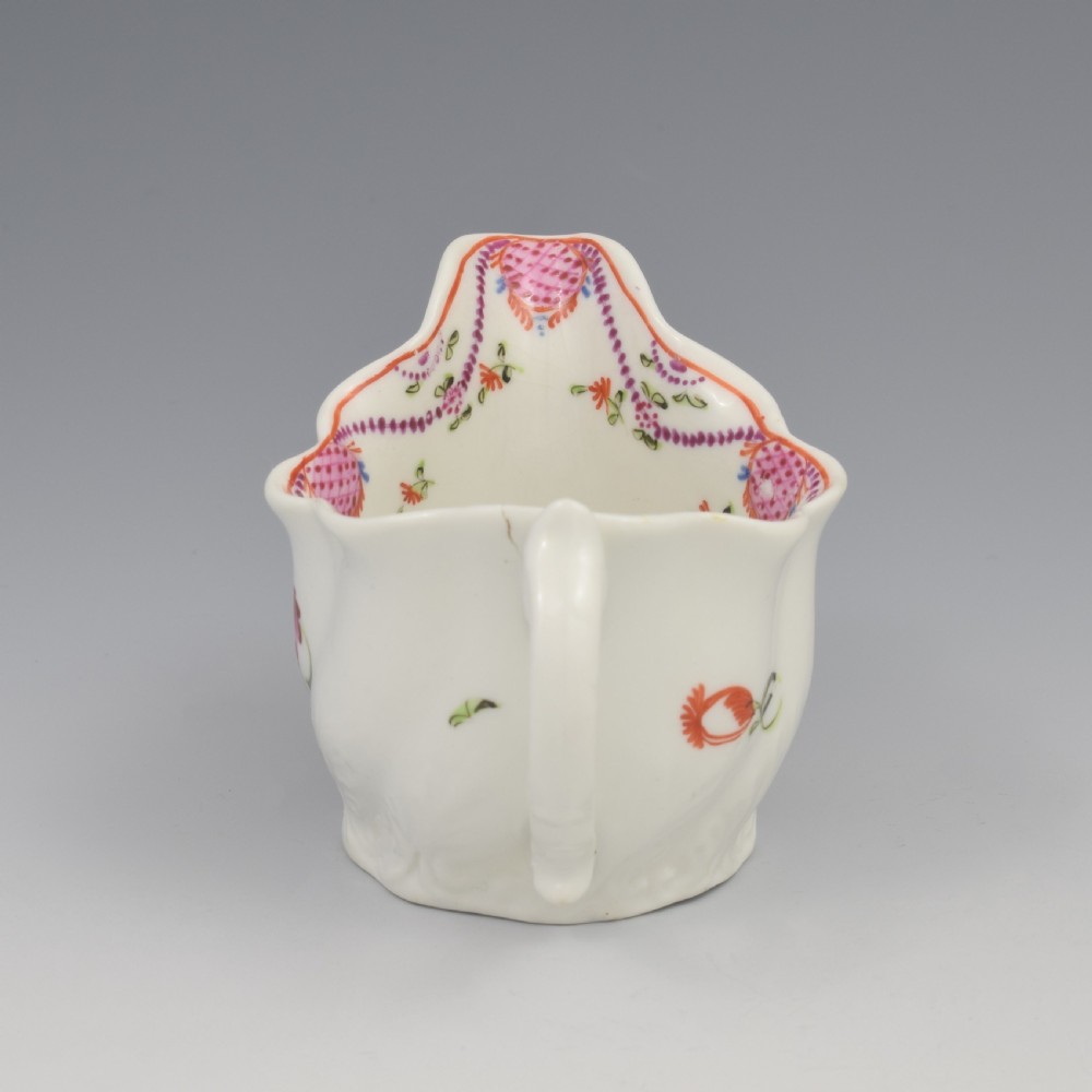 A white porcelain low Chelsea ewer cream jug featuring hand-painted pink floral sprigs, a moulded leaf base, and an ornate loop handle. View VIII