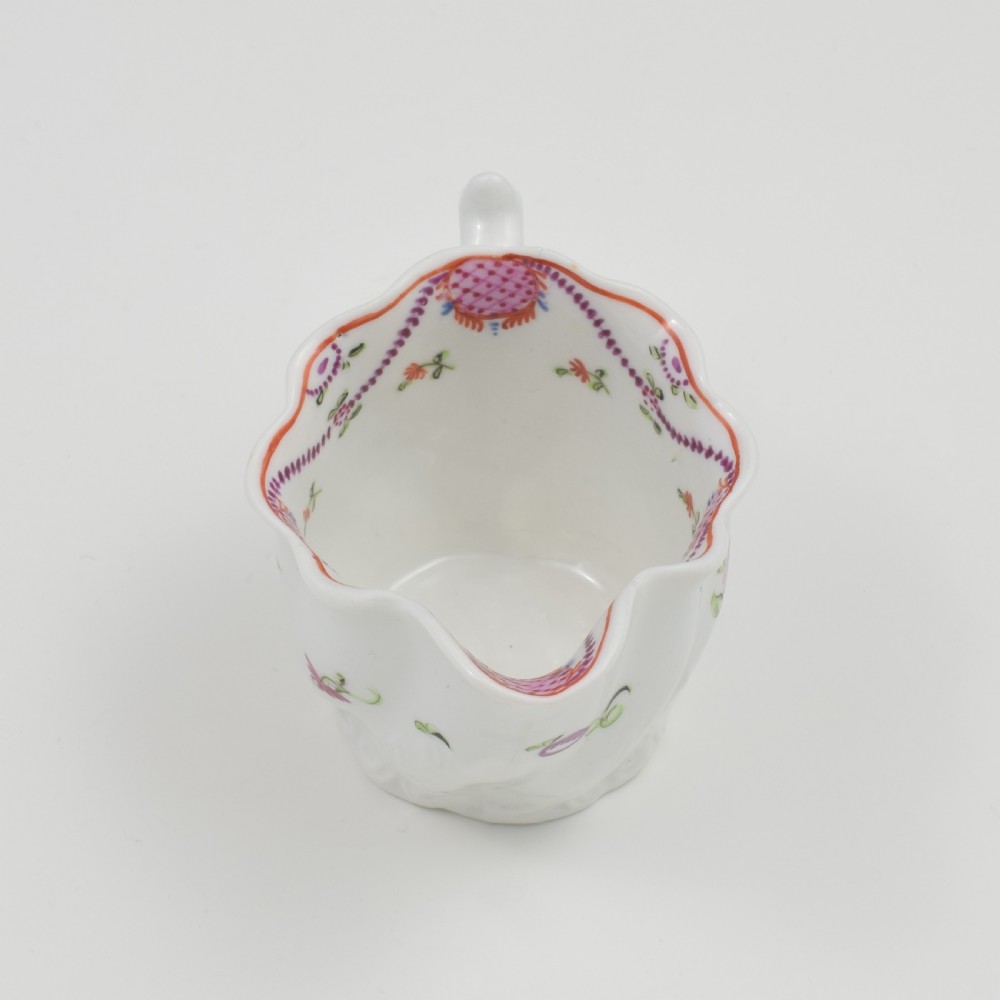 A white porcelain low Chelsea ewer cream jug featuring hand-painted pink floral sprigs, a moulded leaf base, and an ornate loop handle. View XI