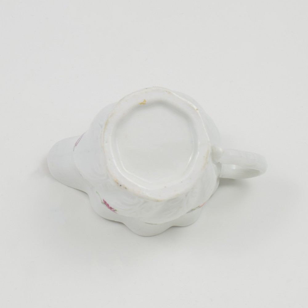 A white porcelain low Chelsea ewer cream jug featuring hand-painted pink floral sprigs, a moulded leaf base, and an ornate loop handle. View XIII