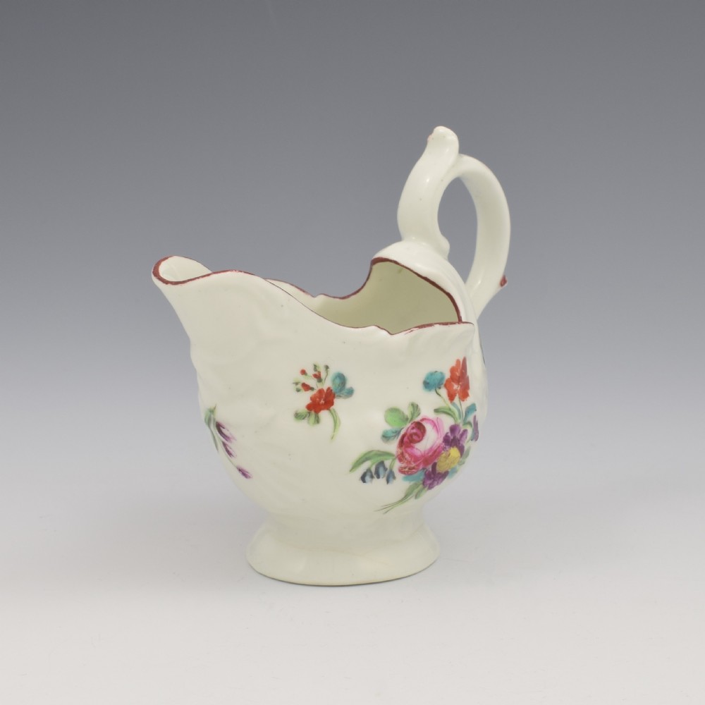 A Georgian Derby soft-paste porcelain cream boat with hand-painted floral motifs and a shaped loop handle on a pedestal base. View II