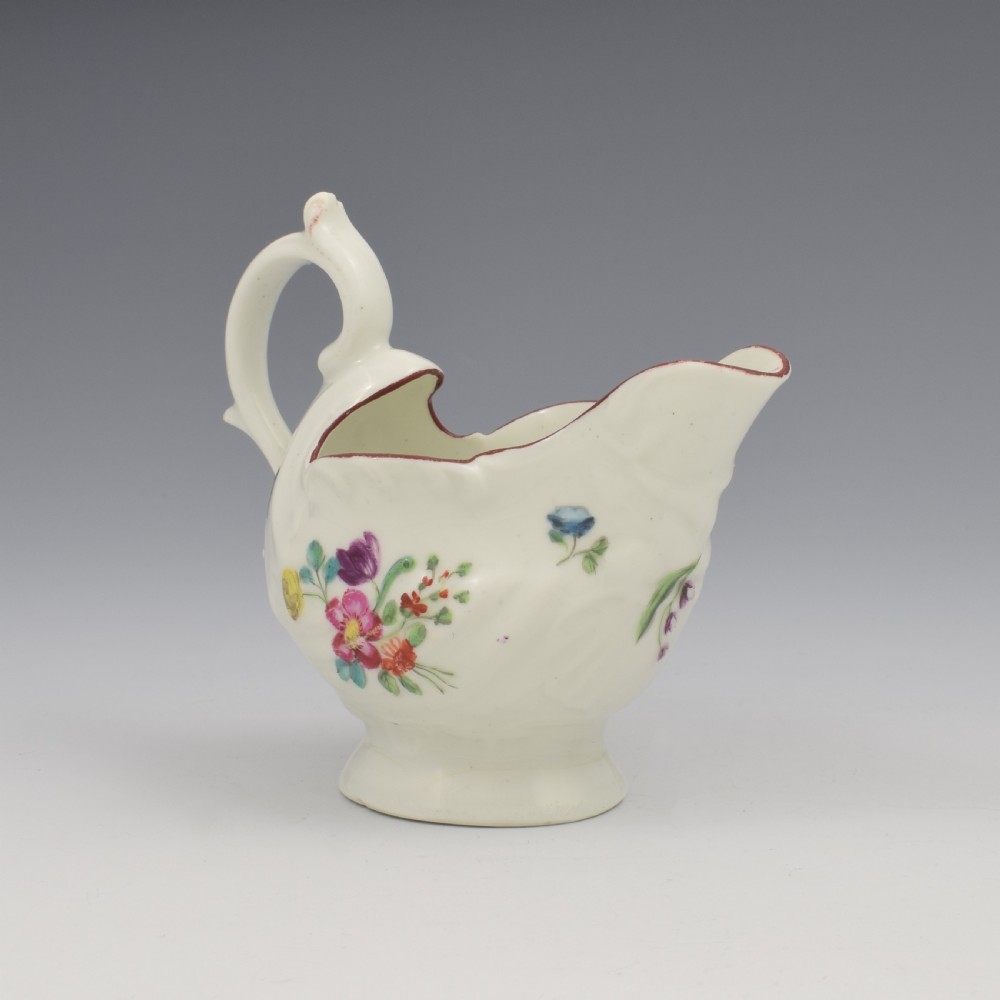 A Georgian Derby soft-paste porcelain cream boat with hand-painted floral motifs and a shaped loop handle on a pedestal base. View IV