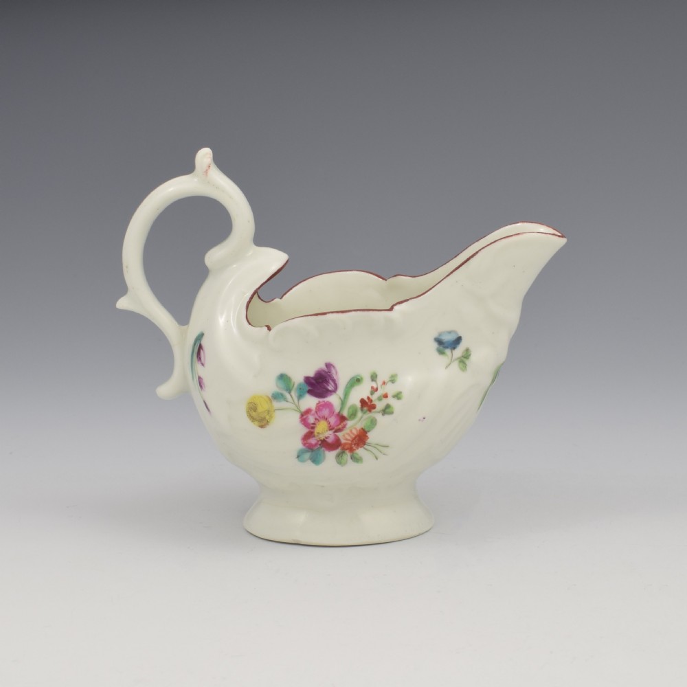 A Georgian Derby soft-paste porcelain cream boat with hand-painted floral motifs and a shaped loop handle on a pedestal base. View V