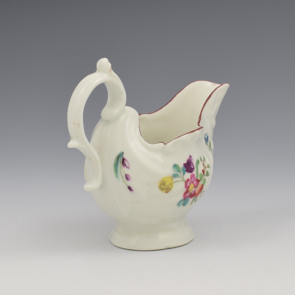 A Georgian Derby soft-paste porcelain cream boat with hand-painted floral motifs and a shaped loop handle on a pedestal base. View VI