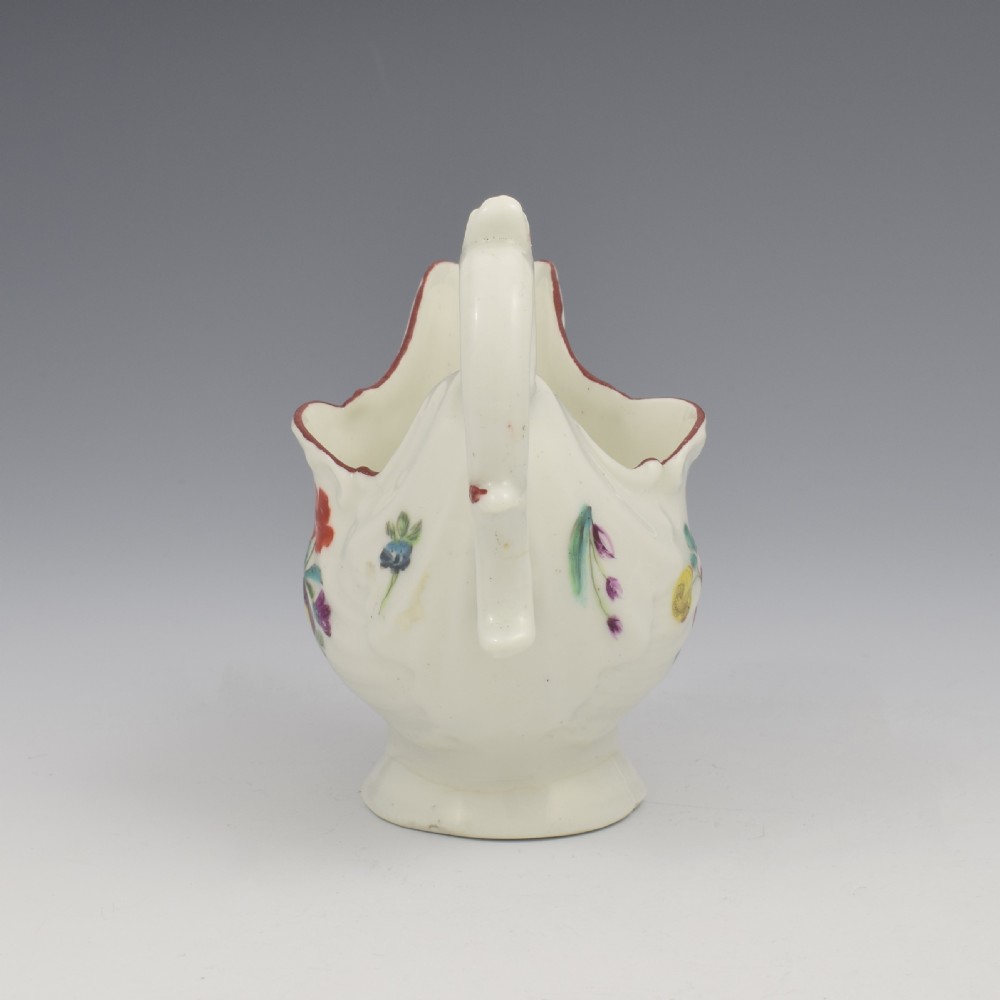 A Georgian Derby soft-paste porcelain cream boat with hand-painted floral motifs and a shaped loop handle on a pedestal base. View VII