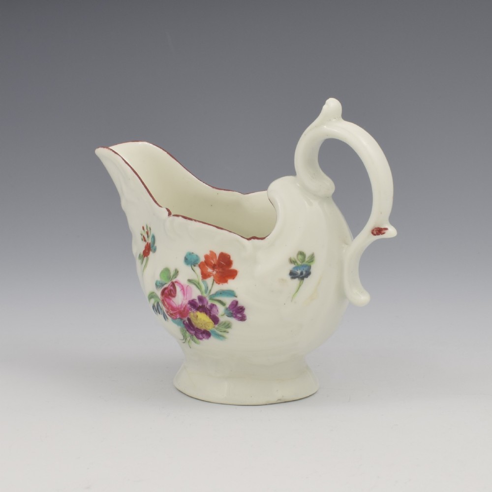A Georgian Derby soft-paste porcelain cream boat with hand-painted floral motifs and a shaped loop handle on a pedestal base. View VIII