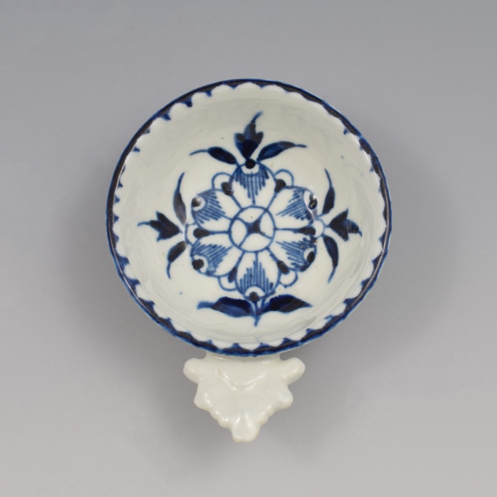 An eighteenth-century Derby soft-paste porcelain circular wine taster featuring hand-painted underglaze blue floral motifs and a shell-moulded handle. View III